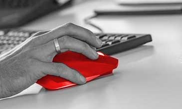 Dieses Bild zeigt eine Hand auf einer Computermaus inklusive Tastatur